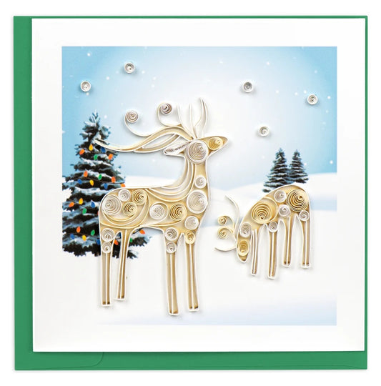 Quilled Snowy Reindeer Holiday Card - two dimensional paper quilled reindeer in cream and gold standing in a snowy winter landscape with lit Christmas trees and snowflakes, green envelope