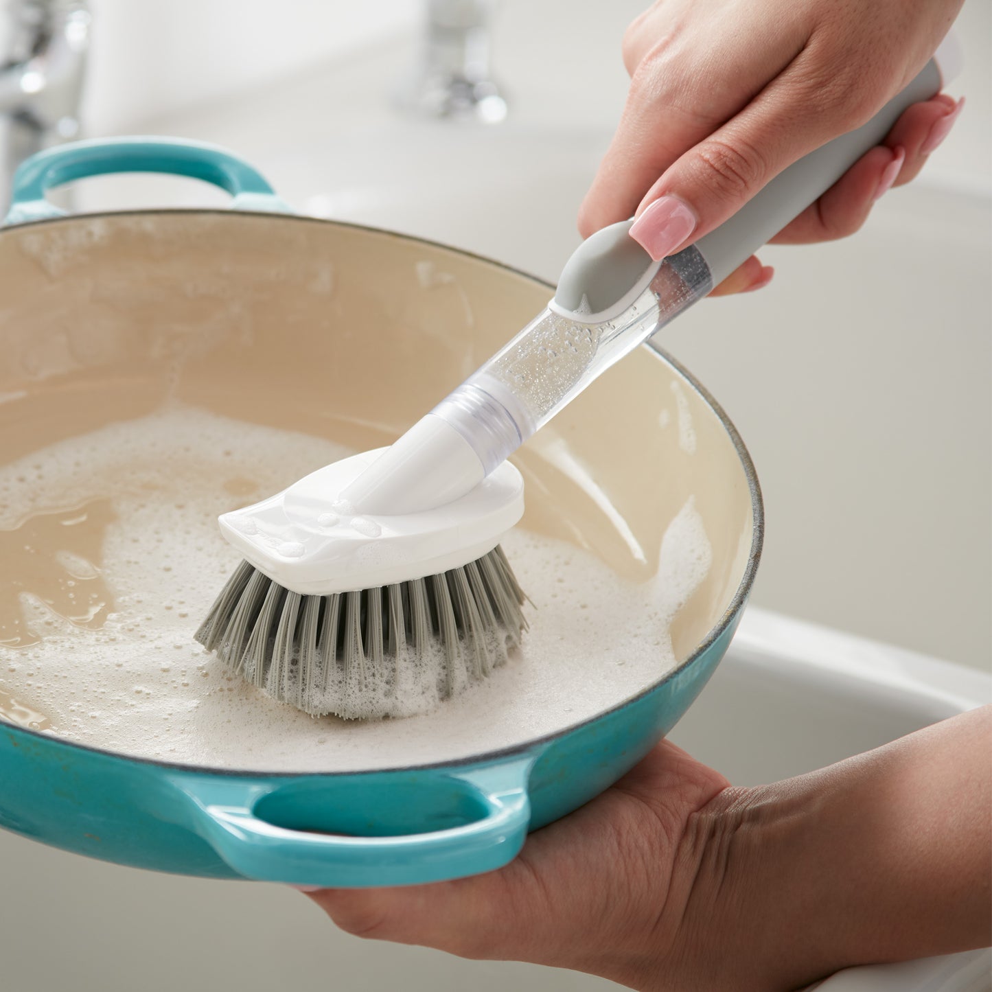 Norwex Soap-Dispensing Kitchen Scrub Brush in use - lathering soap in teal pan